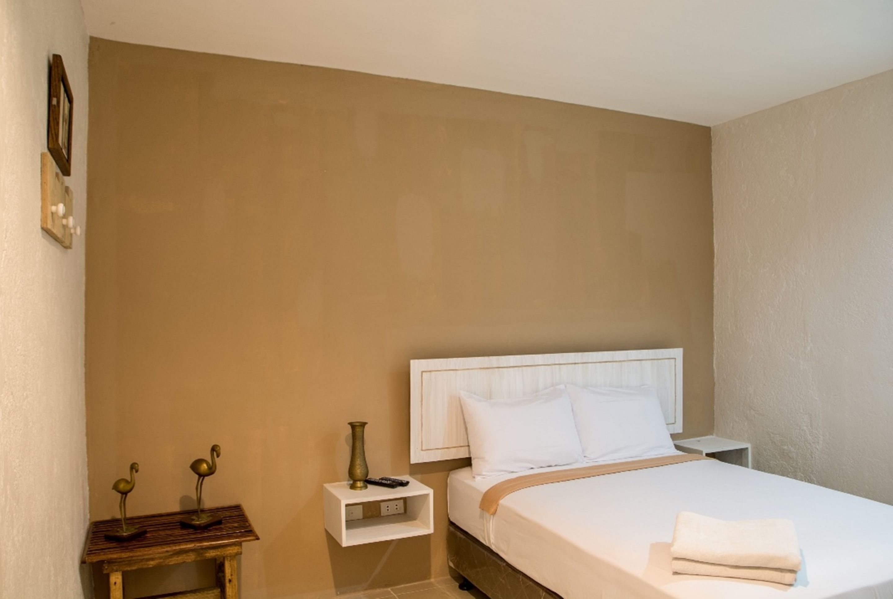 Un dormitorio con cama, mesita de noche y estante en la pared.