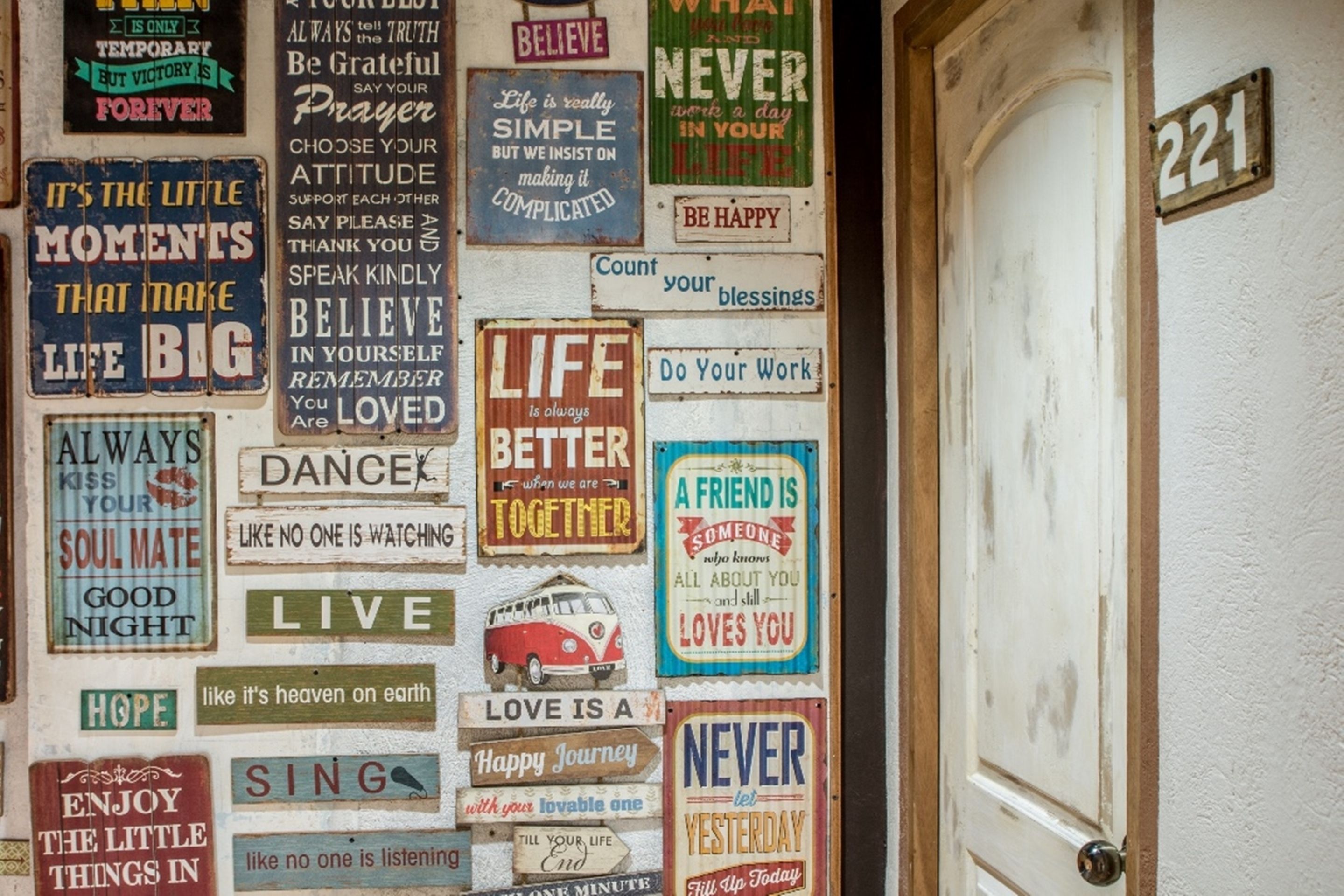 Un mur orné de divers panneaux d’encouragement et une porte portant le numéro 221.
