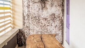 A corner room with a wooden table and metal chairs, a window with blinds, and a textured wall. - Hotel Avenija (Olongapo)