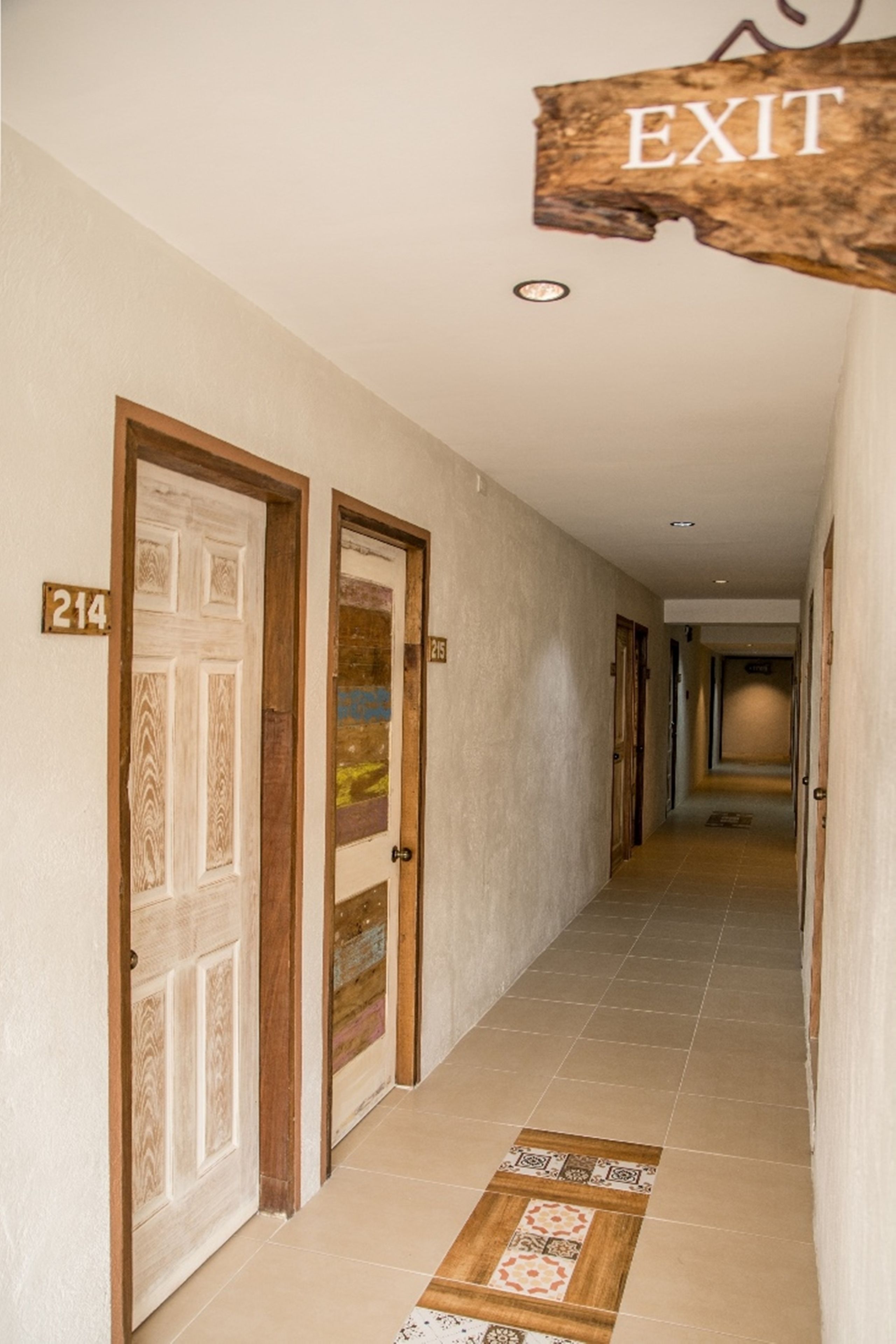 A hallway with two doors, one marked with the number 214, and an exit sign above.