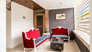 A cozy room with two red upholstered sofas, a small table with a decorative bowl, and a clock on the wall. - Hotel Avenija (Olongapo)