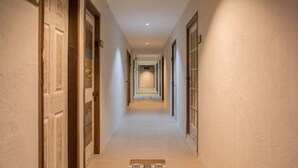 A long, narrow hallway with doors on both sides, leading to a central area. - Hotel Avenija (Olongapo)