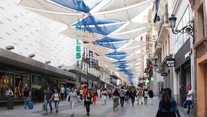 A pedestrian walkway with a modern architectural design, featuring a series of geometric canopies and a variety of shops and eateries. - Hostal Yolanda (Madrid)