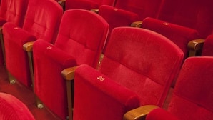 Rows of red theater seats with wooden armrests, each seat labeled with a number. - Hostal Yolanda (Madrid)