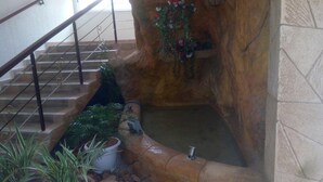 A staircase with a stone wall, a metal railing, and potted plants. - Eifell's Hotel's (Abidjan)