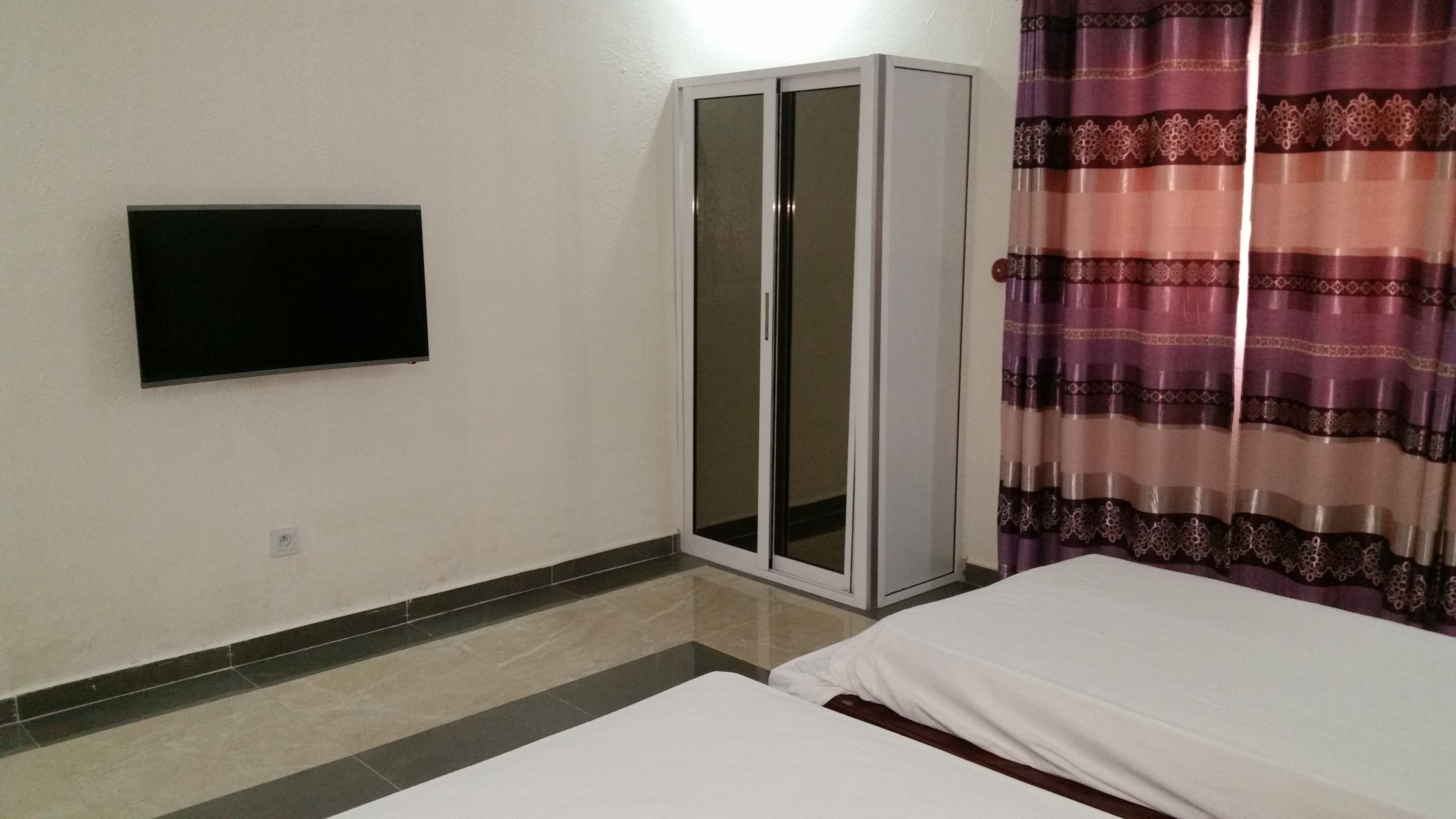 A room with a bed, a wardrobe, and a television on the wall.