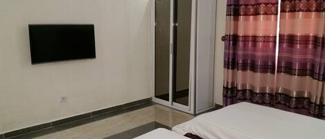 A room with a bed, a wardrobe, and a television on the wall.