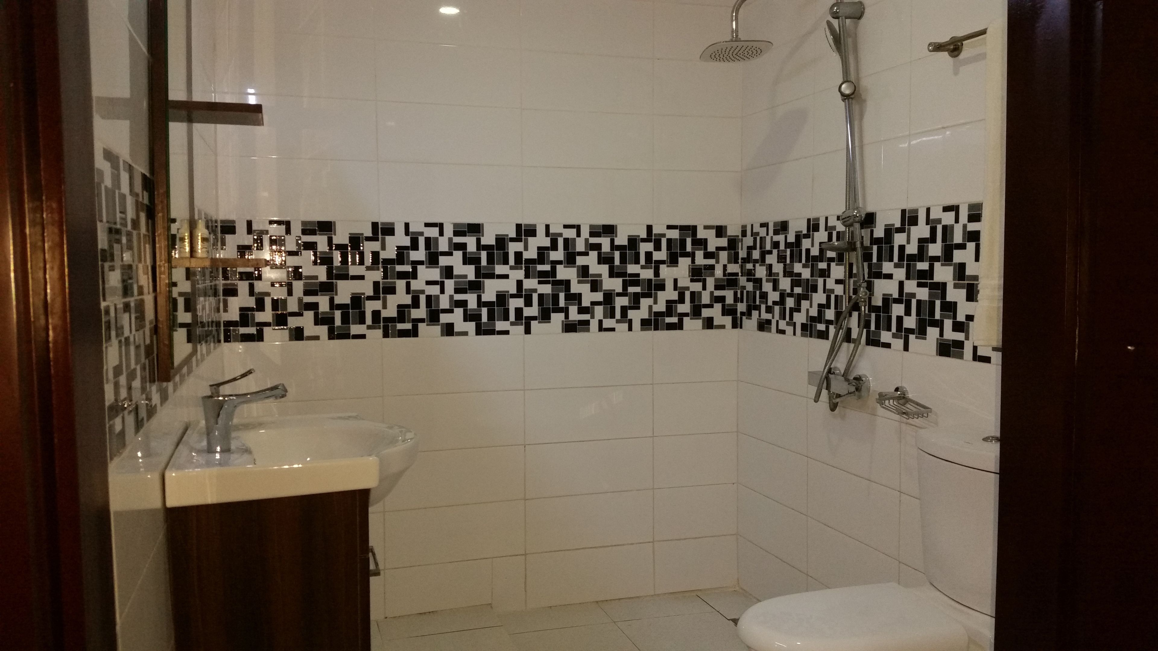 Casa de banho com lavatório branco, sanita e chuveiro.