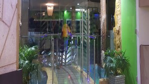 A hotel entrance with a glass door, a staircase, and a modern chandelier. - Eifell's Hotel's (Abidjan)