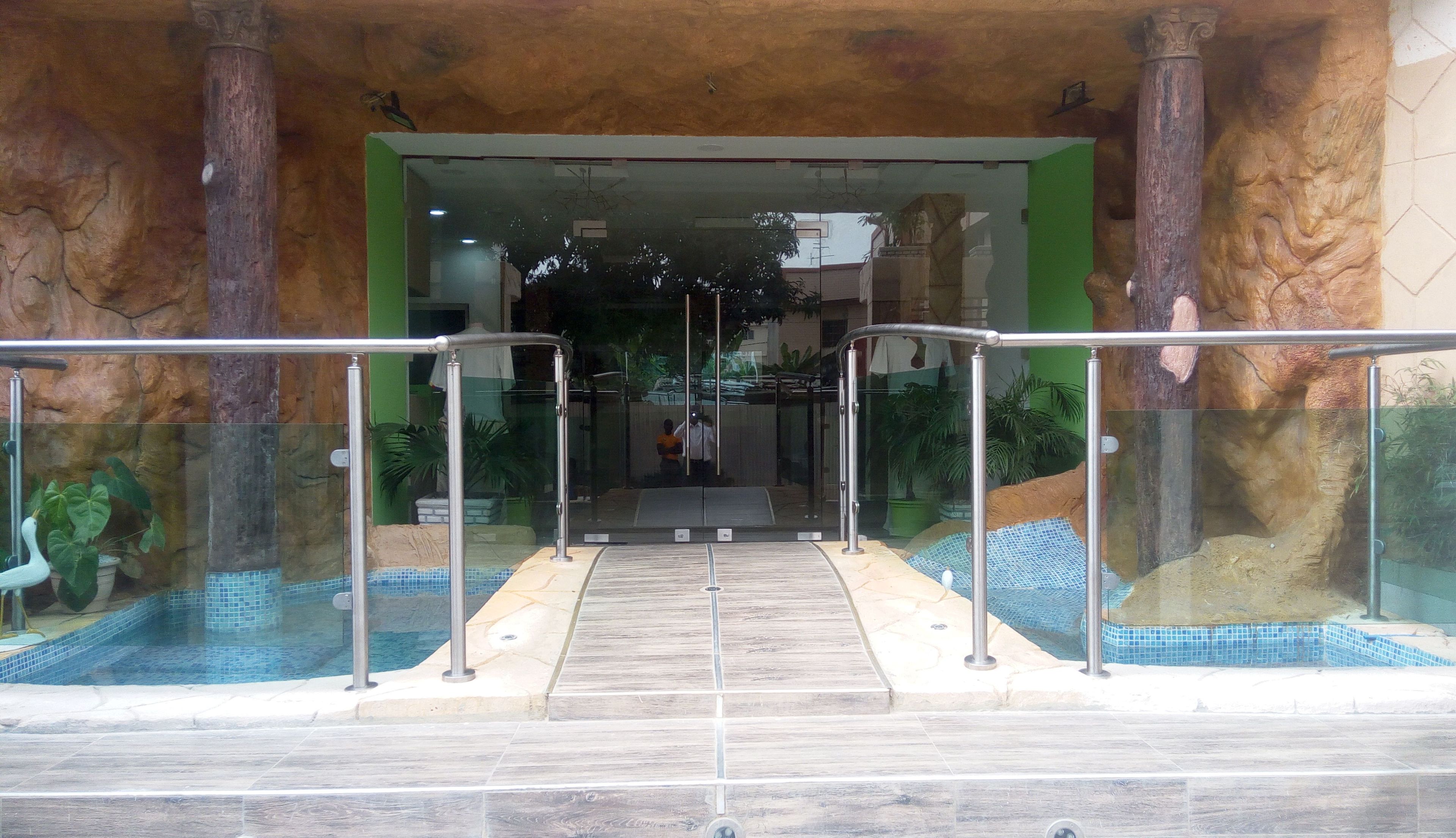 A pool area with a glass enclosure, a wooden deck, and metal railings.