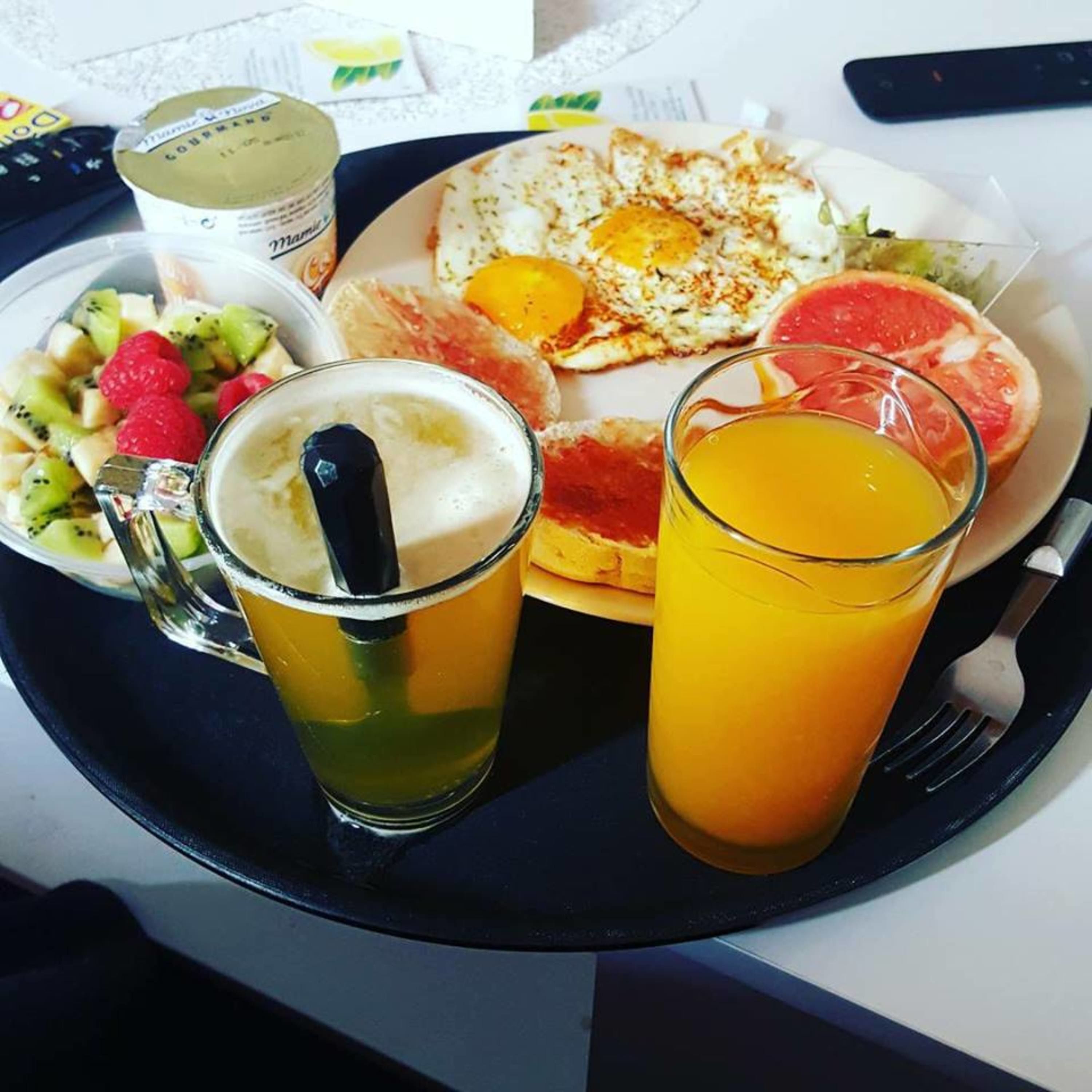 Ein Frühstücksbrett mit Eiern, Toast, Obst, einem Glas Orangensaft und einer Tasse Kaffee.