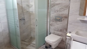 A bathroom with a glass-enclosed shower, a toilet, and a sink. - Asya Bungalow (Kemer)