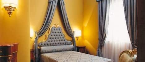 A hotel room with a bed, a nightstand, a chair, and a desk.