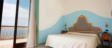 A bedroom with a bed, a nightstand, a window with curtains, and a view of the outside.