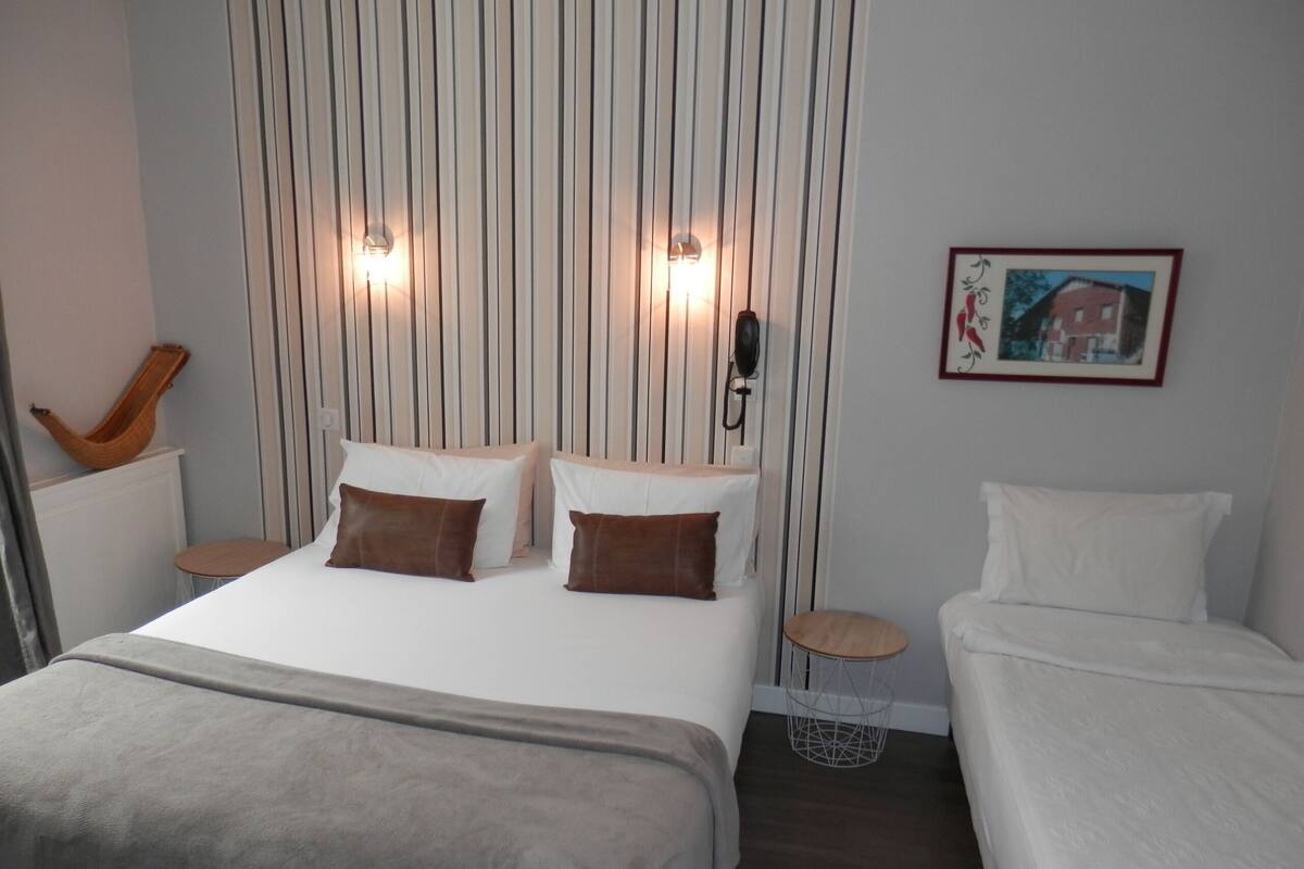 A hotel room with a bed, two bedside tables, a small round table, and a wall-mounted telephone.