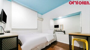 A hotel room with a bed, a desk, a chair, a TV, and a mirror. - Ace Motel (Gangneung)