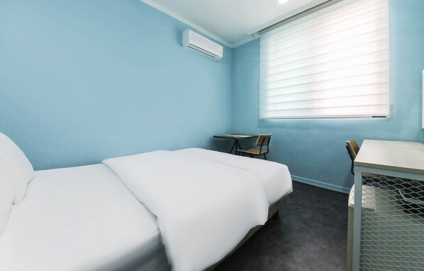 Una habitación con una cama individual, un escritorio y una silla.