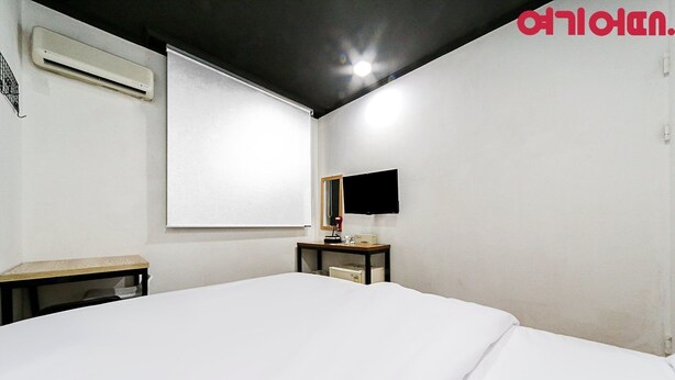 A room with a bed, a desk, a chair, a flat-screen TV, and a wall-mounted air conditioner. - Ace Motel (Gangneung)