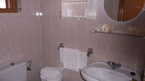 A bathroom with a toilet, sink, and mirror. There is a towel rack with a folded towel and a glass shelf above the sink. - Hotel Arce (San Pedro del Pinatar)