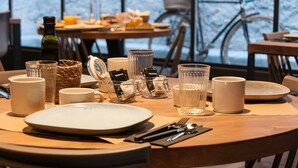 A dining table set with plates, cups, and a bottle, with a view of bicycles outside. - Hotelet de Sant Joan (Sant Joan de Les Abadesses)