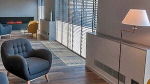 A modern living room with a fireplace, comfortable seating, and large windows. - Hotelet de Sant Joan (Sant Joan de Les Abadesses)