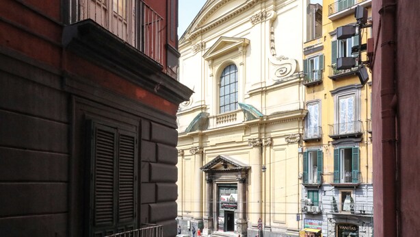 A narrow street with historic buildings, including a church with a prominent entrance and a sign for 'Vanitas'. - Toledo 16 Luxury Suites (Naples)