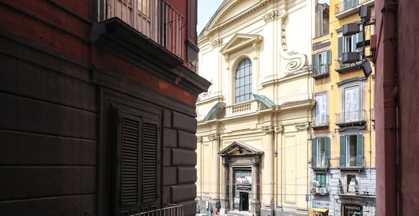 A narrow street with historic buildings, including a church with a prominent entrance and a sign for 'Vanitas'. - Toledo 16 Luxury Suites (Naples)