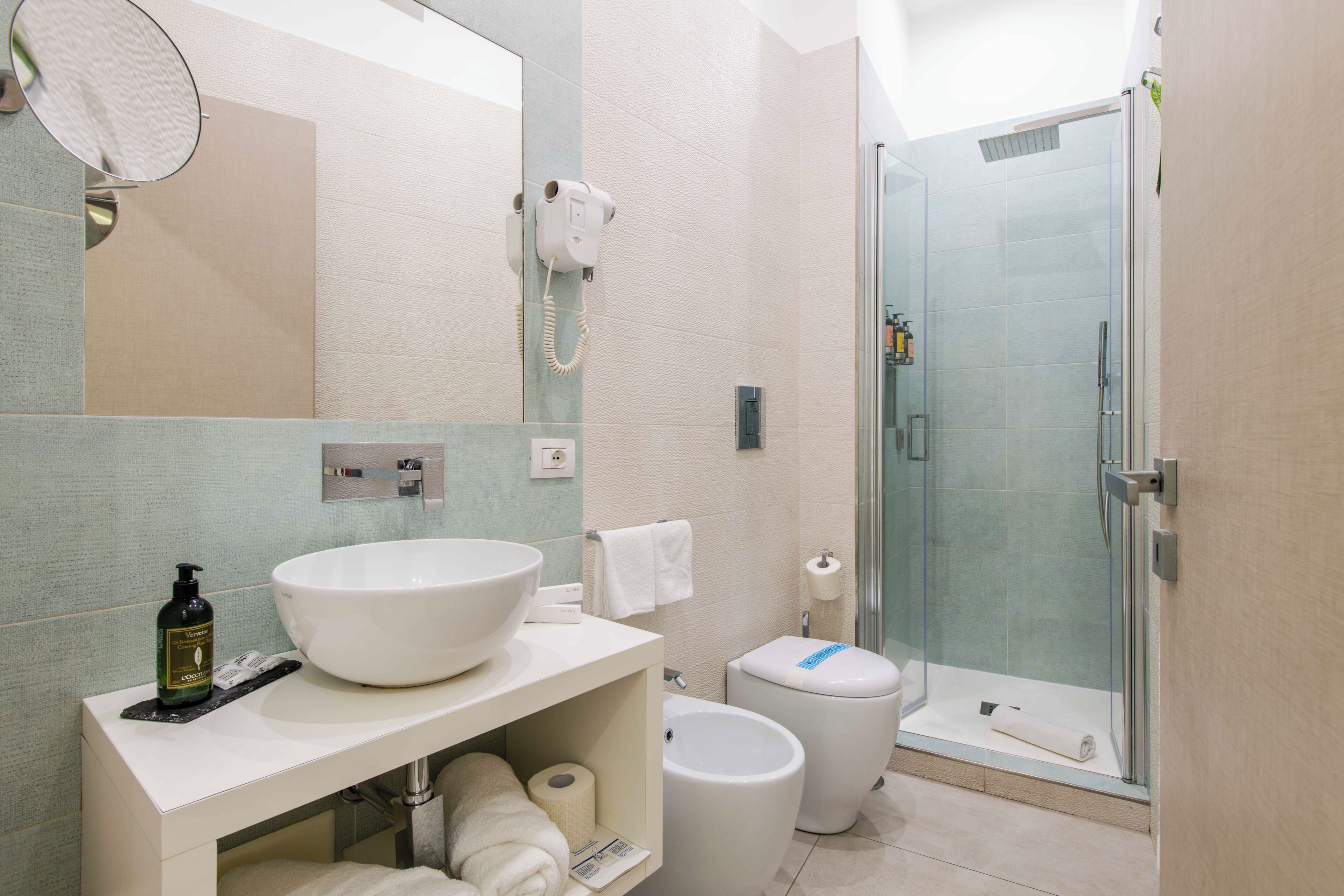 Un baño moderno con un lavabo grande de color blanco, un inodoro, una zona de ducha y un espejo.
