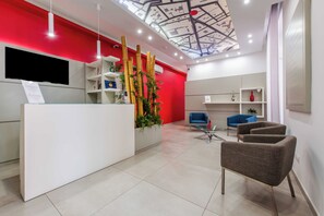 A reception area with a modern design, featuring a reception desk, seating area, and a ceiling with a map design. - Toledo 16 Luxury Suites (Naples)