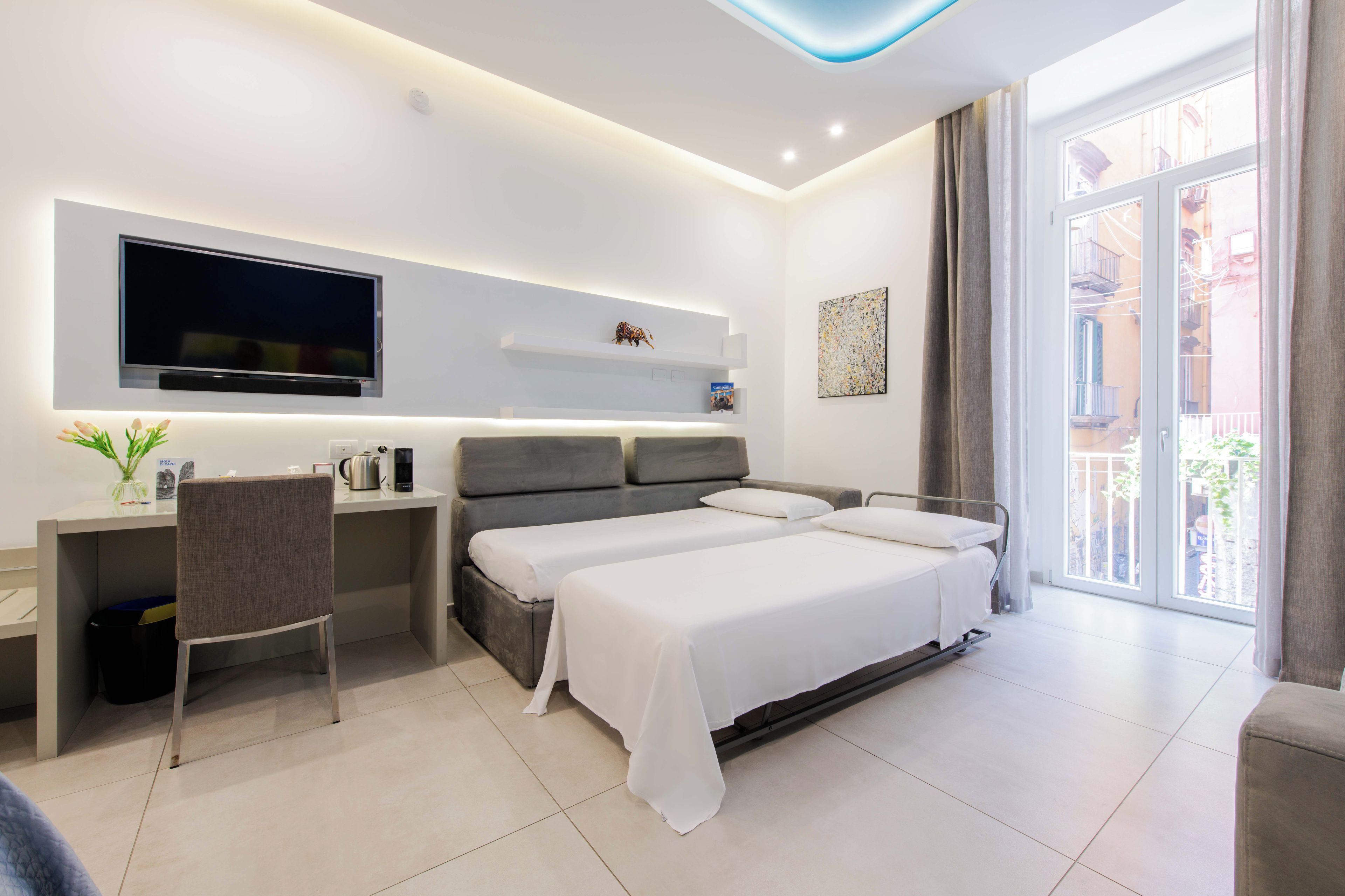 Une chambre d’hôtel moderne équipée d’un lit, d’un bureau, d’une chaise, d’une télévision et d’œuvres d’art.