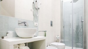 A modern bathroom with a large white sink, a glass shower enclosure, and a toilet with a white lid. - Toledo 16 Luxury Suites (Naples)