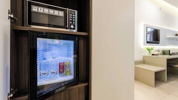 A modern kitchen with a built-in refrigerator, microwave, and a flat-screen TV mounted above the counter.
