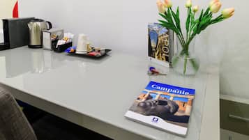 Een bureau met een brochure, een vaas met tulpen, een dienblad met snacks en een koffiezetapparaat.