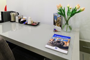 A desk with a brochure, a vase with tulips, a tray with snacks, and a coffee maker. - Toledo 16 Luxury Suites (Naples)