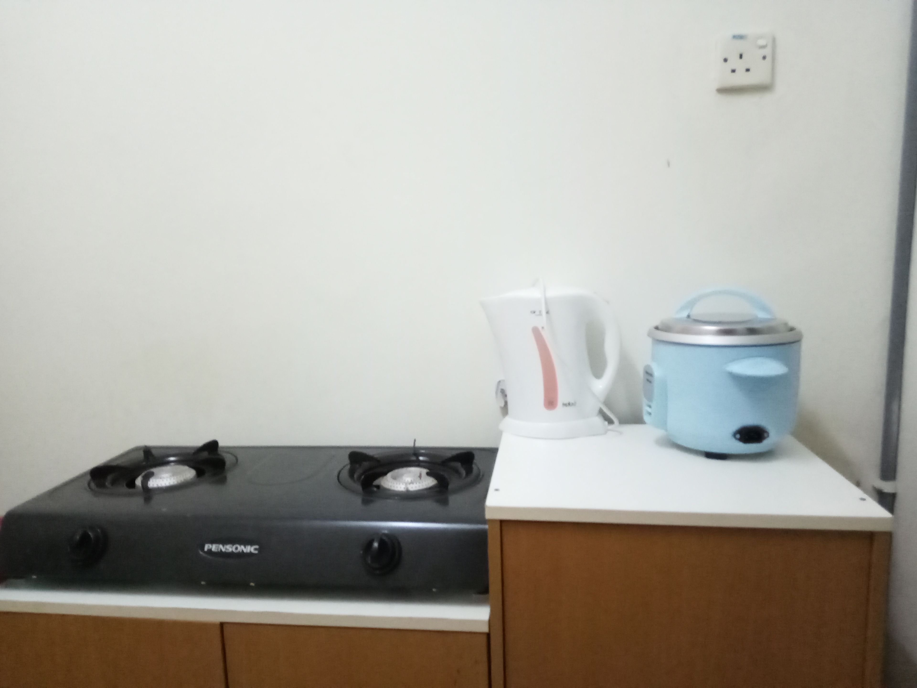 A kitchen with a gas stove, a kettle, and a slow cooker on a white countertop.