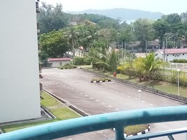 Una carretera con palmeras y un edificio al fondo.