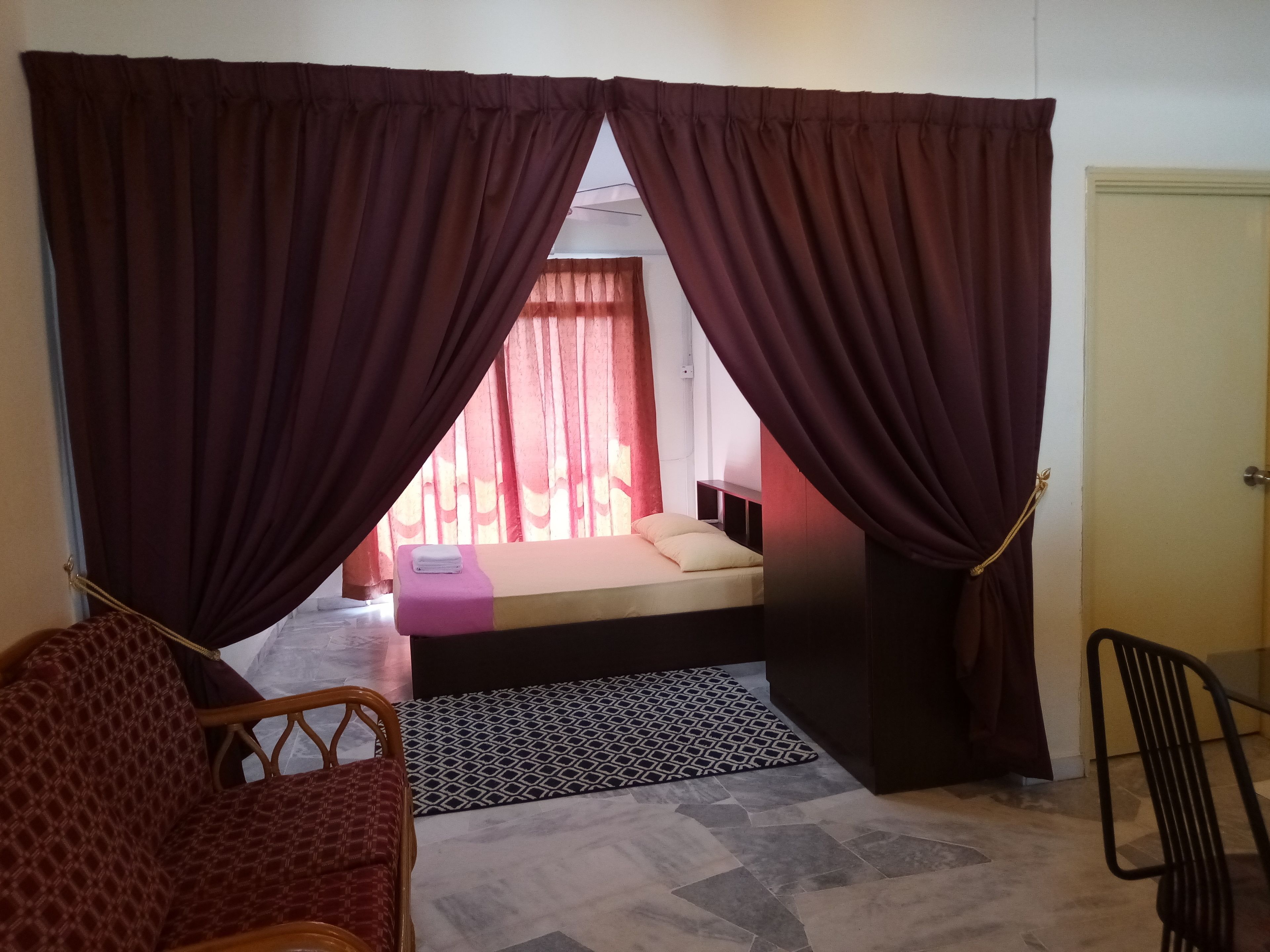 A room with a bed, a chair, and a door.