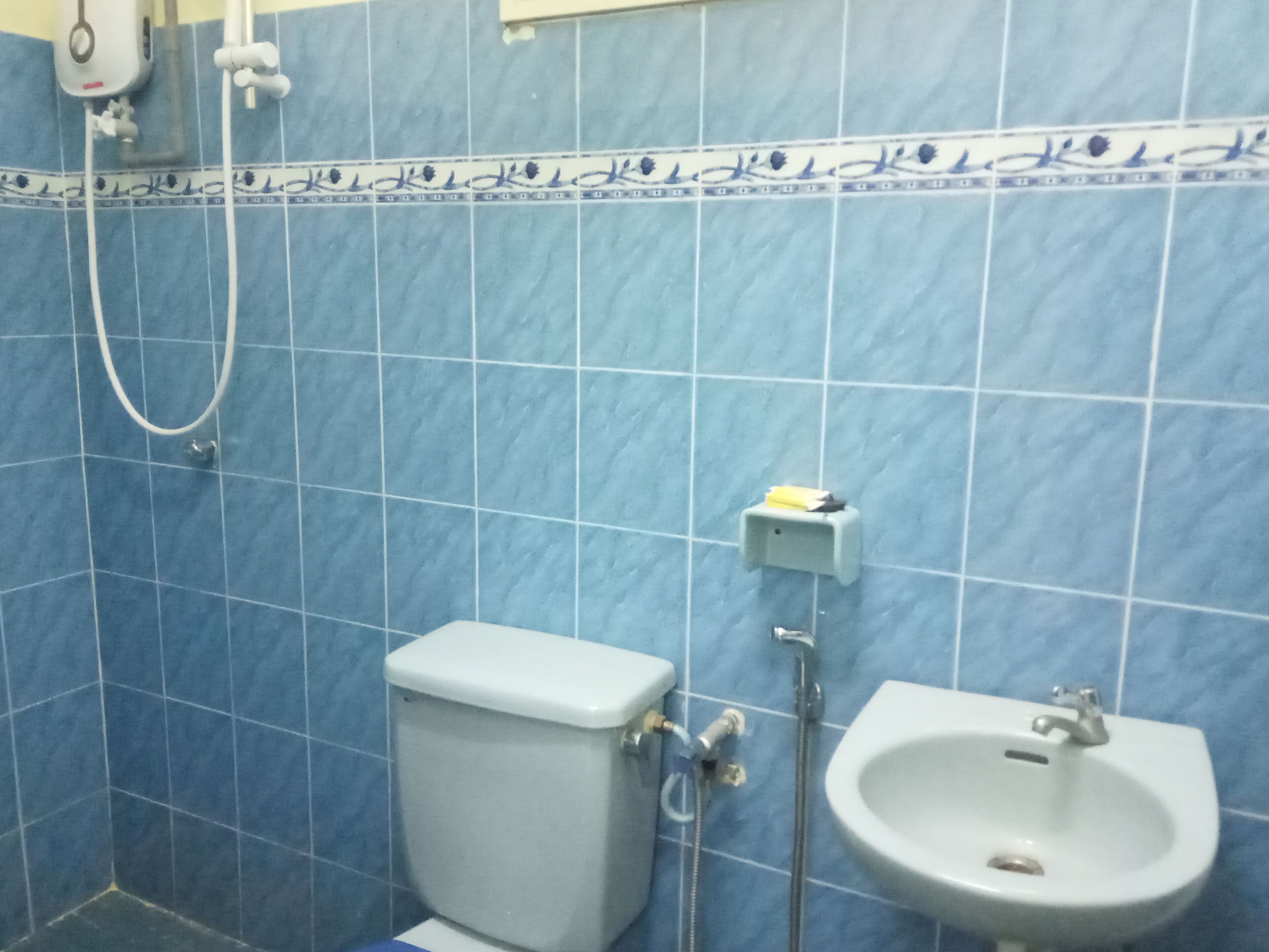 Ein Badezimmer mit blauen Fliesen, Toilette, Waschbecken und Dusche.