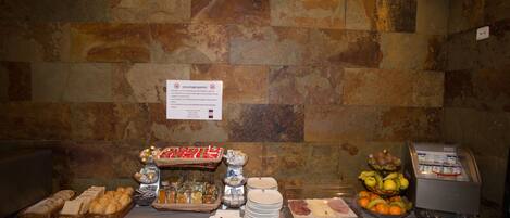 Uma mesa de buffet com diversos alimentos e um espaço para bebidas de serviço por autoatendimento.
