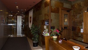 A hotel reception area with a wooden reception desk, a potted plant, and a reception counter. - Hotel Yerri (Estella)
