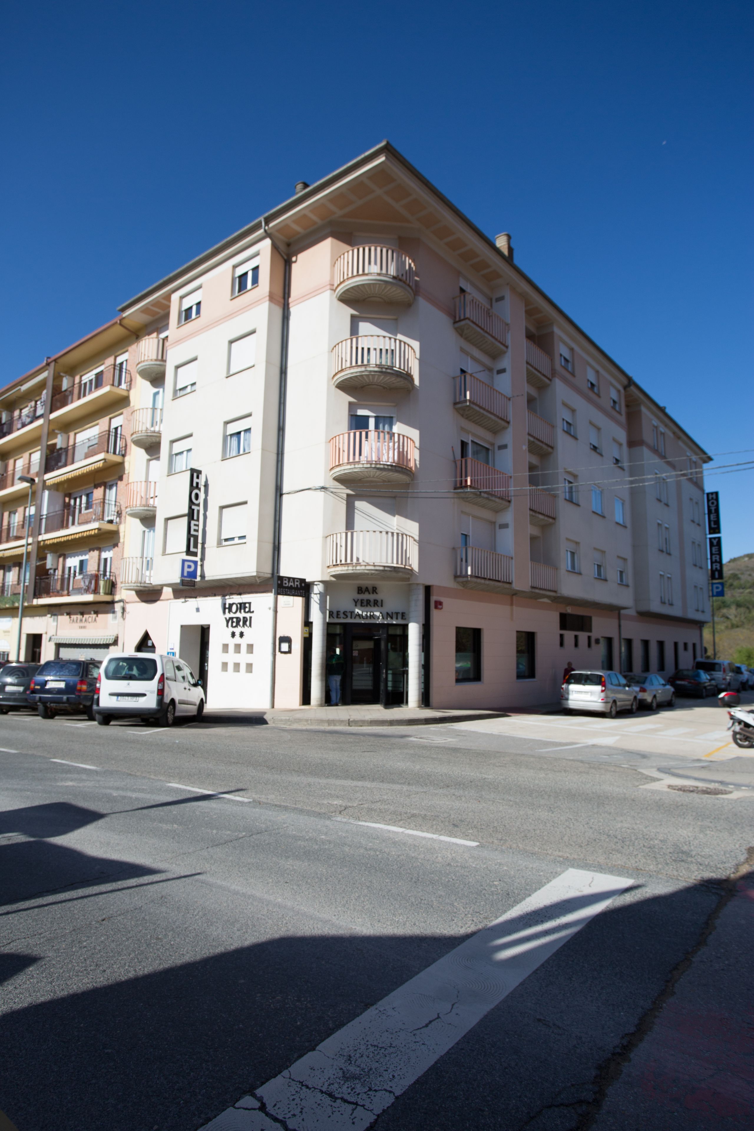 A multi-story hotel with balconies, a parking area, and a restaurant.