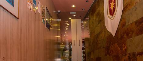 A hotel corridor with wooden walls, a marble floor, and a red ceiling.