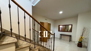 Eine Treppe mit Holnläufen und Steinstufen führt zu einer Zwischenebene mit einer Bank und einem Spiegel an der Wand.