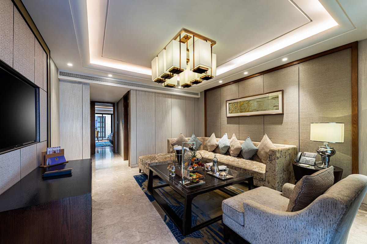 Un hall d’hôtel moderne avec un canapé, des fauteuils, une table basse, un téléviseur et une œuvre d’art encadrée accrochée au mur.