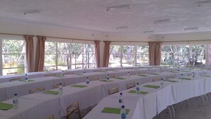 A conference room with multiple tables, chairs, and water bottles, large windows with curtains, and a tiled floor. - Nora Valley Lodge (Harare)
