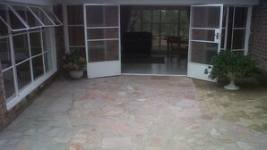 A stone-floored patio with glass doors leading to an interior space. - Nora Valley Lodge (Harare)