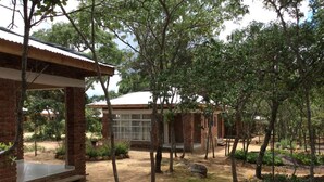 A brick building with a covered patio and a large window. - Nora Valley Lodge (Harare)