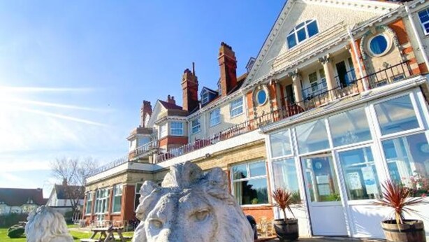 A stately building with a large glass facade, a prominent balcony, and two lion statues in the foreground.