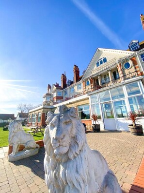 A stately building with a large glass facade, a prominent balcony, and two lion statues in the foreground. - Skegness The Royal Hotel (Skegness)
