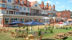 A hotel with a patio area featuring outdoor seating and umbrellas.